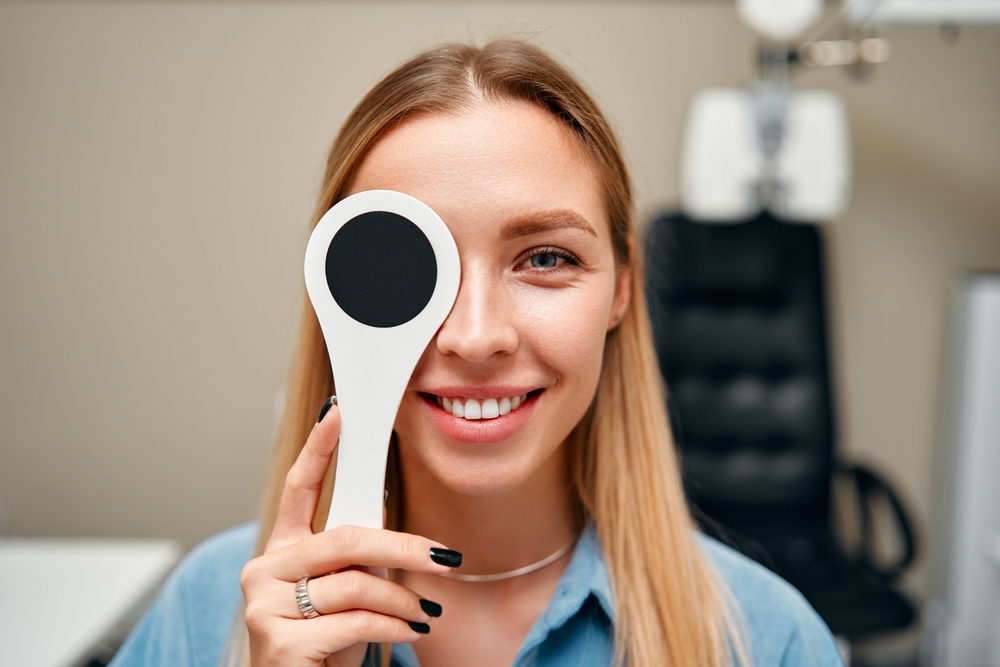 An optometrist helps a patient try on glasses while sitting at a desk with a computer displaying eyewear options - Carlson Eye Care An optometrist helps a patient try on glasses while sitting at a desk with a computer displaying eyewear options - Carlson Eye Care - Eye Doctor Grandville MI