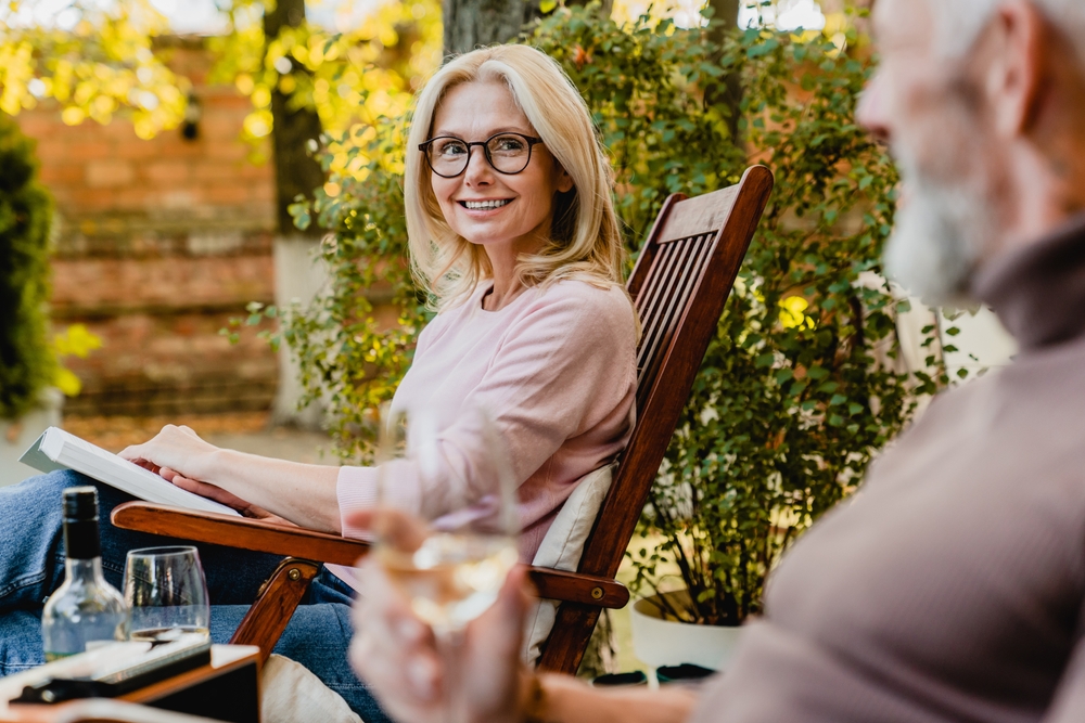 An optometrist helps a patient try on glasses while sitting at a desk with a computer displaying eyewear options - Carlson Eye Care Woman outdoors wearing glasses - Eye Doctor in Rockford